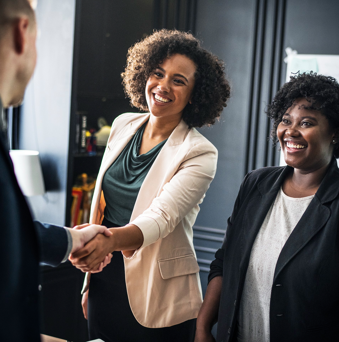 Woman shaking hands with man as another observes